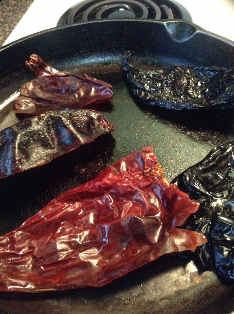 Dried chiles roasting on a cast-iron skillet